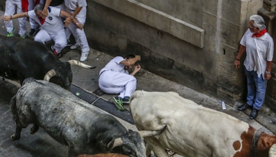 Un corredor caído se protege ante la presencia de los toros sevillanos. (Lander FERNANDEZ DE ARROYABE/ARGAZKI PRESS)