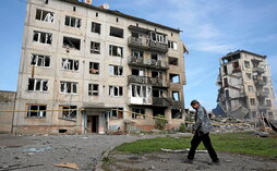 Un hombre camina junto a varios edificios de apartamentos destruidos en Ocheretyne, cerca de la ciudad de Avdiivka.