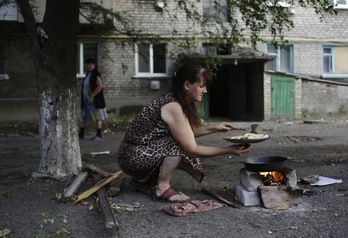 Una mujer emplea una hoguera para cocinar en plena calle. (Anatolii SEPANOV/AFP)