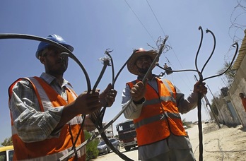 Trabajadores palestinos tratan de reparar la destrozada red eléctrica de Gaza. (Said KHATIB / AFP)