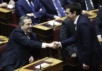 El primer ministro griego, Alexis Tsipras, saluda a su predecesor en el cargo, Antonis Samaras. (Yannis KOLESIDIS/AFP PHOTO)