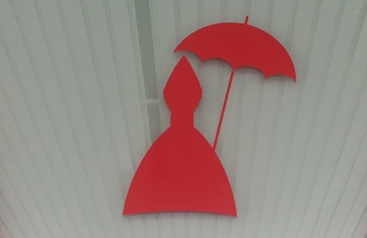 Curioso San Fermín dotado con un paraguas en lugar del báculo que se puede ver en Arrotxapea.